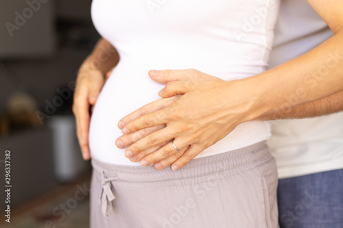 Wallpaper Mural Expectant couple standing indoors close to each other. Hands of man and woman holding big pregnant belly. Expecting baby concept Torontodigital.ca