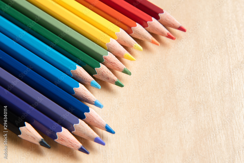 Colored pencils arranged in diagonal line on wooden background Colored pencils arranged in diagonal line on wooden background