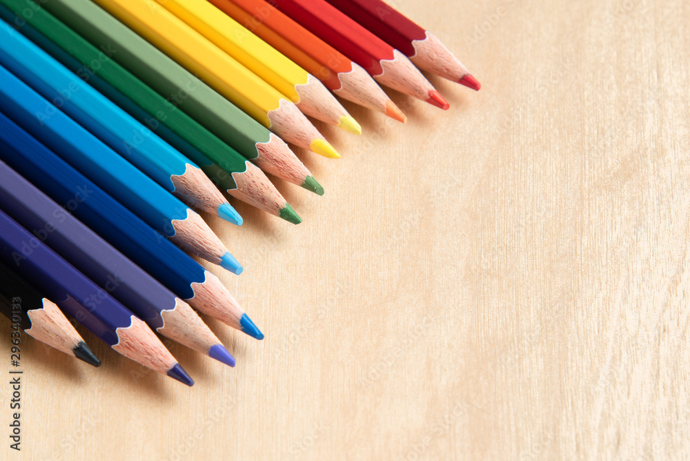Colored pencils arranged in diagonal line on wooden background Colored pencils arranged in diagonal line on wooden background