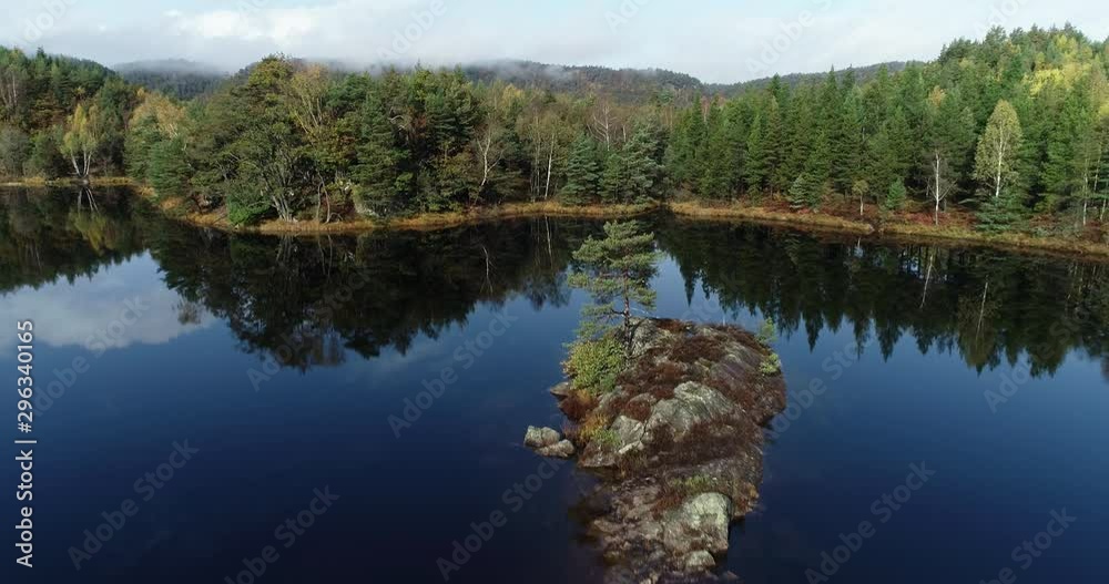 Drone flies towards small rocky island in the middle of a lake. Drone flies towards small rocky island in the middle of a lake.