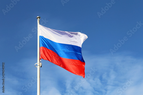 Russian flag waving against the blue sky and white clouds. Symbol of Russia, russian authority concept