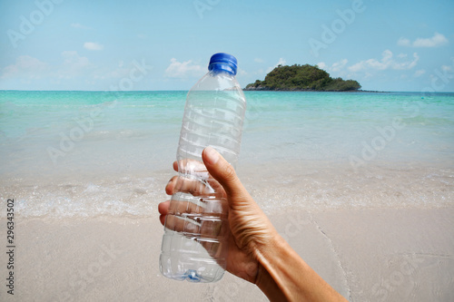 Hand collecting plastic water bottle from sea