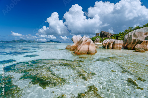Anse Source d'Argent in low tide - Paradise tropical beach with shallow blue lagoon, granite boulders and white clouds above. La Digue island, Seychelles