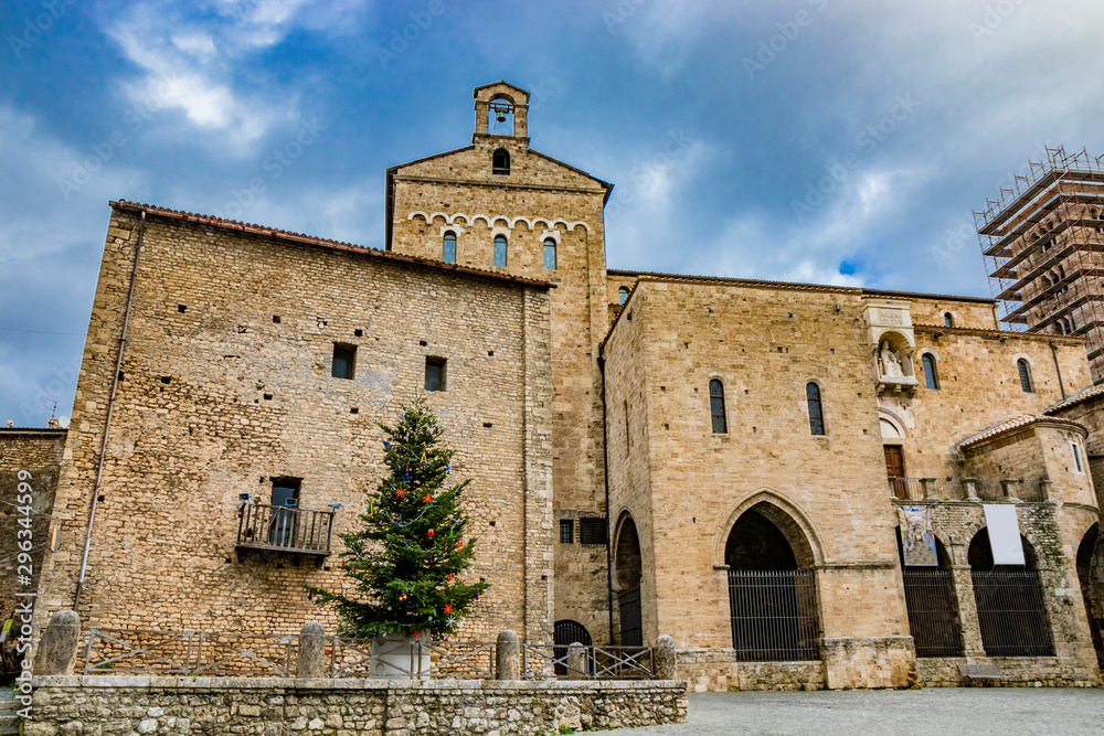A large Christmas tree, decorated with colored balls, festoons and garland, red stars and lights, in the square of the medieval village of Anagni, near the cathedral. Rome, Lazio, Italy.