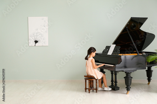 Little girl playing grand piano at home