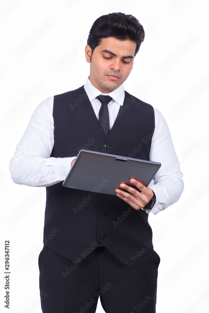 Handsome young businessman using digital tablet. Male entrepreneur is preparing presentation on wireless computer. He is wearing formals on white background.