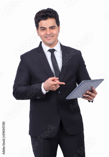 Handsome young businessman pointing at digital tablet on white background