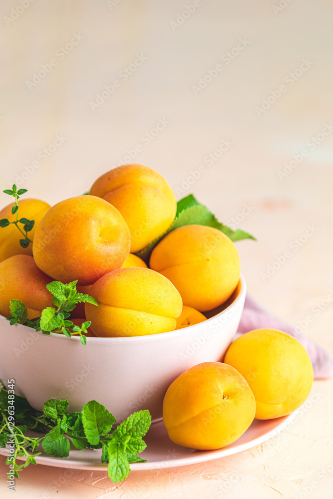 Fresh sweet orange apricots in pink bowl on the pink concrete surface table, selective focus, shallow depth of the fields