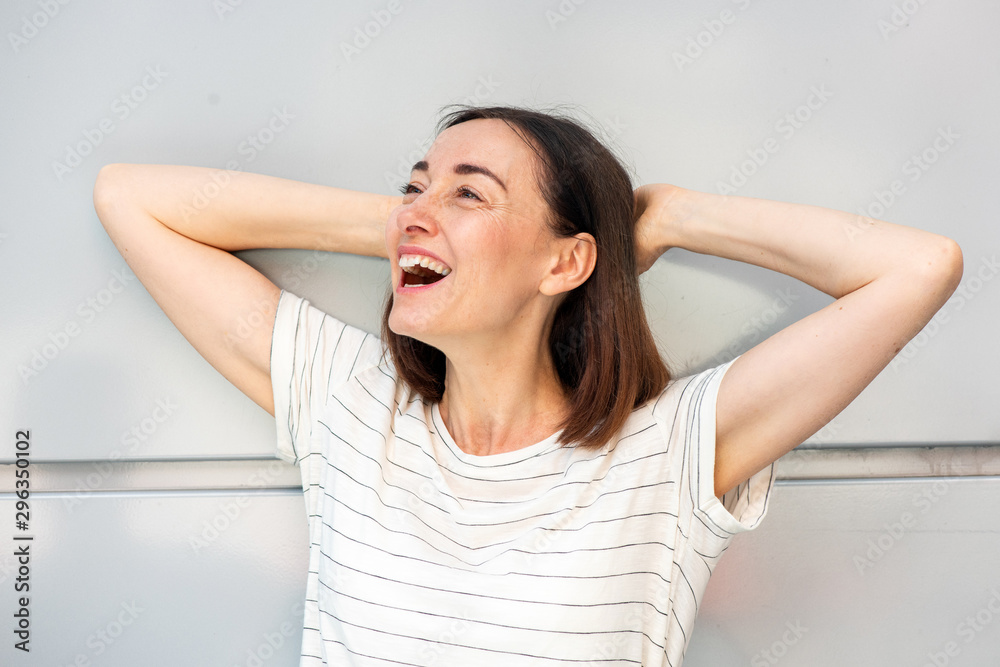 Close up older woman laughing with hand behind head Close up older woman laughing with hand behind head