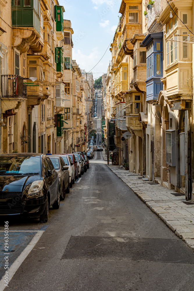 Typical Valletta street architecture with traditional Maltese wooden enclosed balconies and rising road, at Valletta, Malta
