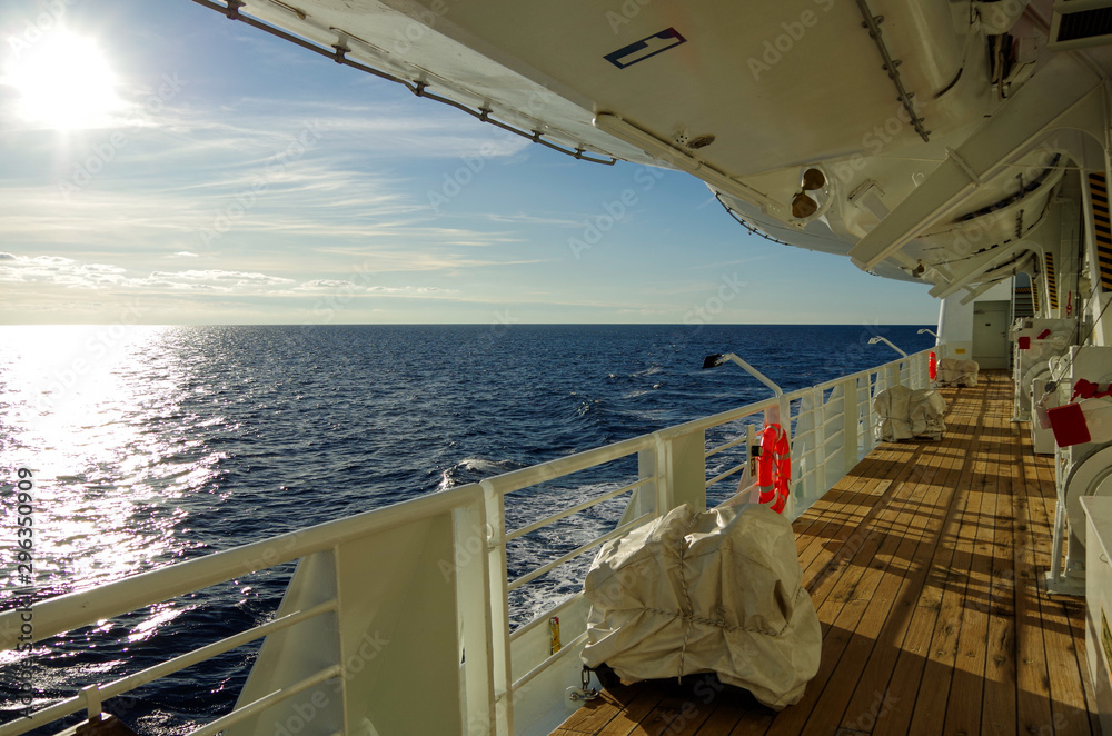Hölzernes Bootsdeck auf Kreuzfahrtschiff Ocean Majesty von Hansa Touristik auf See in Adria bei Sonnenschein - obrazy, fototapety, plakaty 