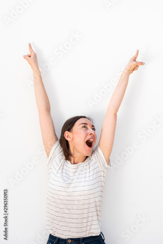 joyful older woman cheering with arms raised by white background