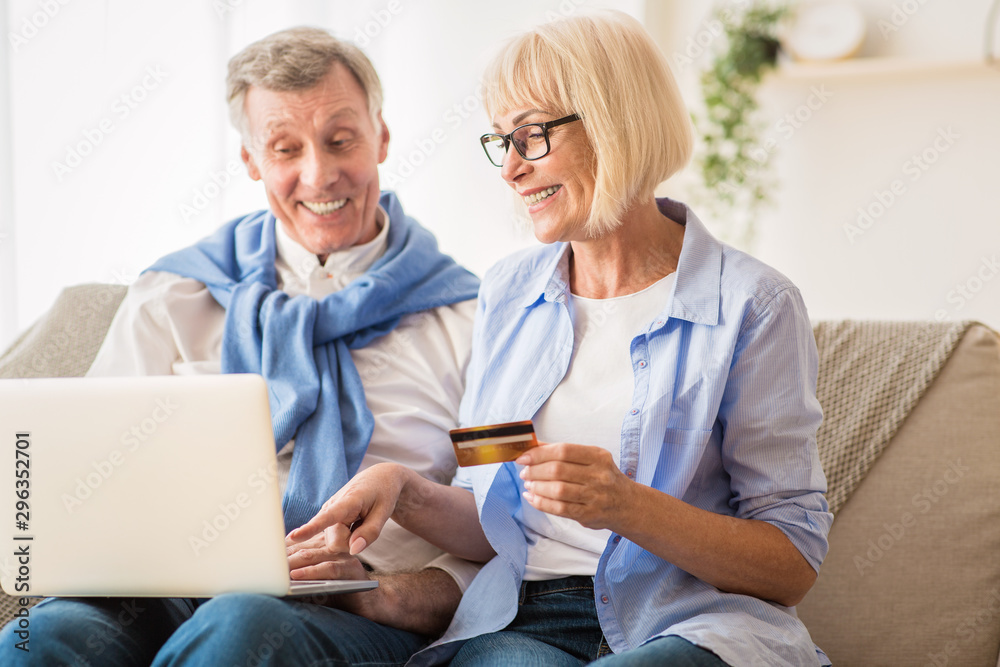 E-Commerce. Mature couple using laptop and credit card
