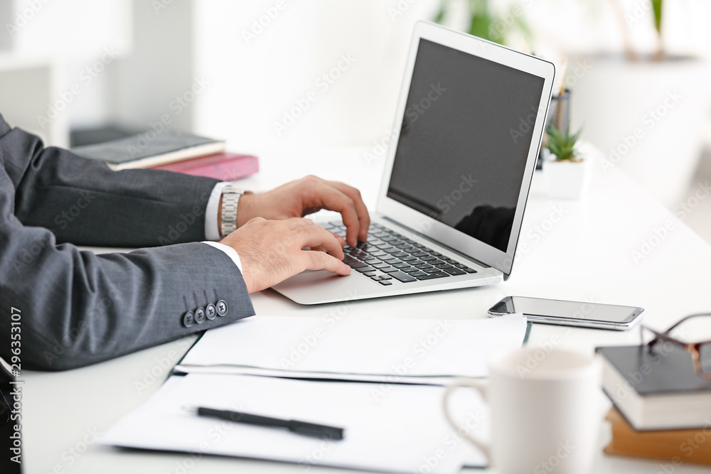 Businessman working on laptop in office, closeup Businessman working on laptop in office, closeup