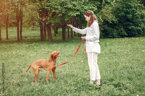 Beautiful girl in a white shirt. Woman in a summer park. Lady with a dog