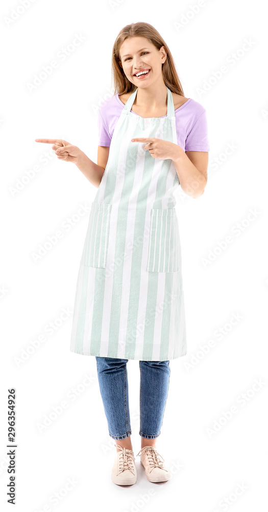 Beautiful young woman in apron pointing at something on white background Beautiful young woman in apron pointing at something on white background