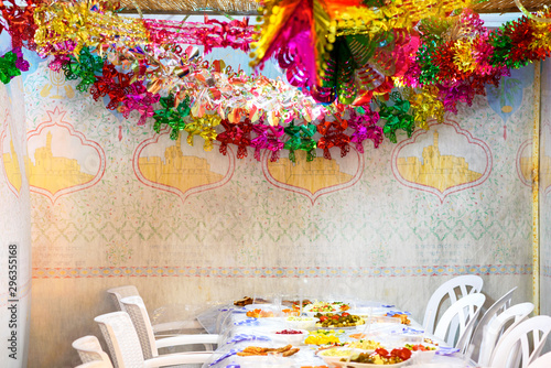 Colorful Sukkah decoration shiny garland and table. Happy family celebrate Sukkot. photo