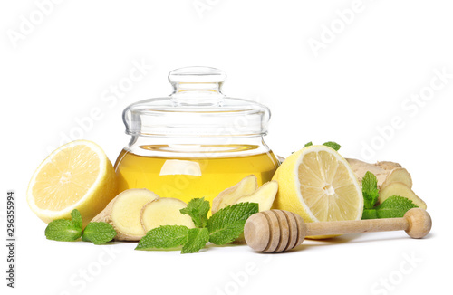 glass jar full of honey and dipper, ginger, lemon and mint isolated on a white background