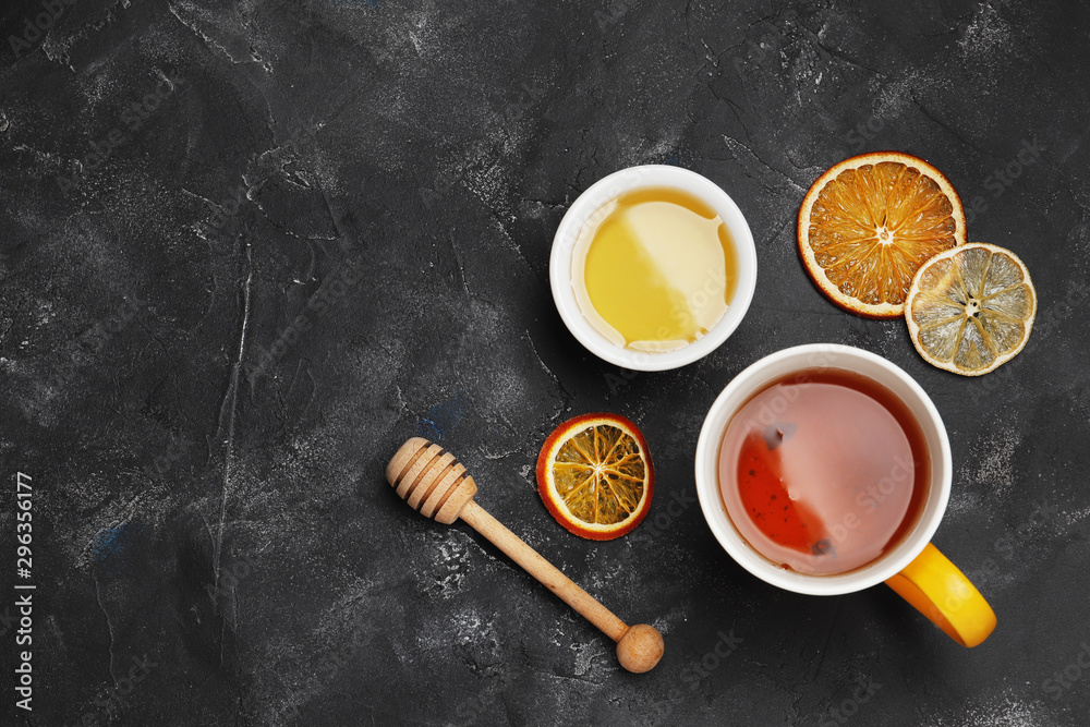 Fototapeta premium A cup of tea close-up on a dark background with dry citruses and honey. Top view.
