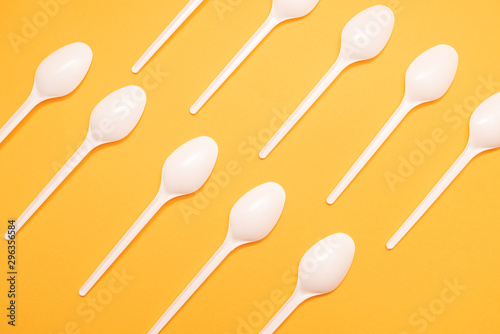 many plastic spoons on yellow background