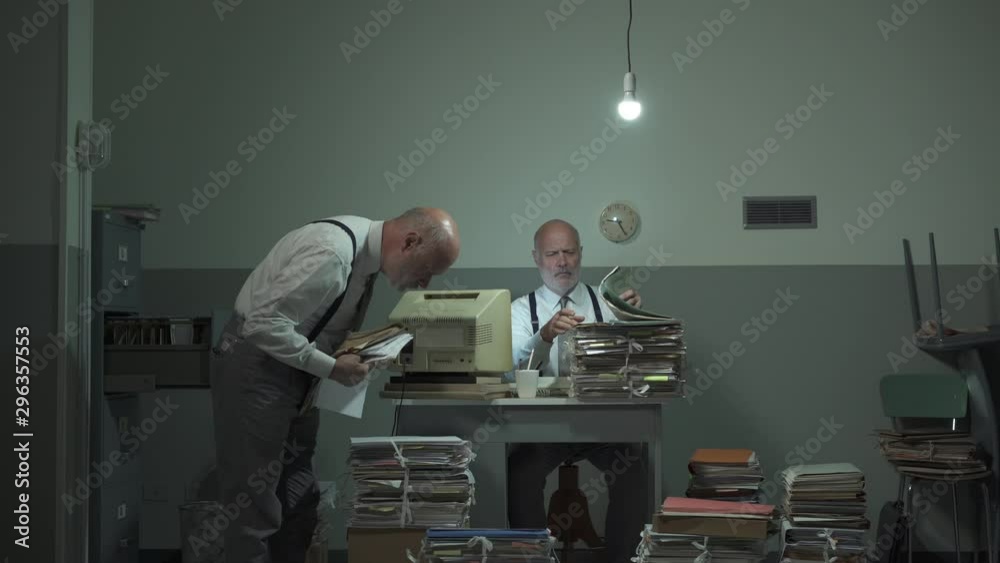 Multitasking office worker searching for files in his office