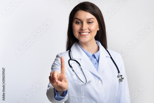 Doctor Woman Touching Invisible Touchscreen Standing Over Gray Background