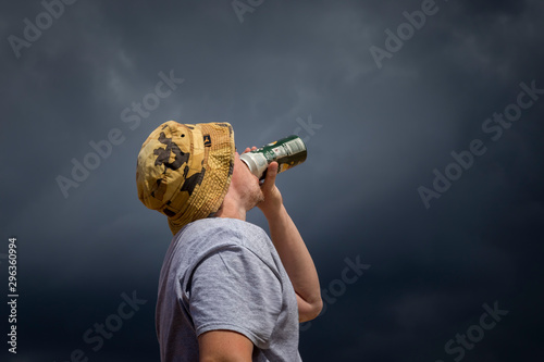 Slika na platnu hatted man drinking alcohol with appraoching storm