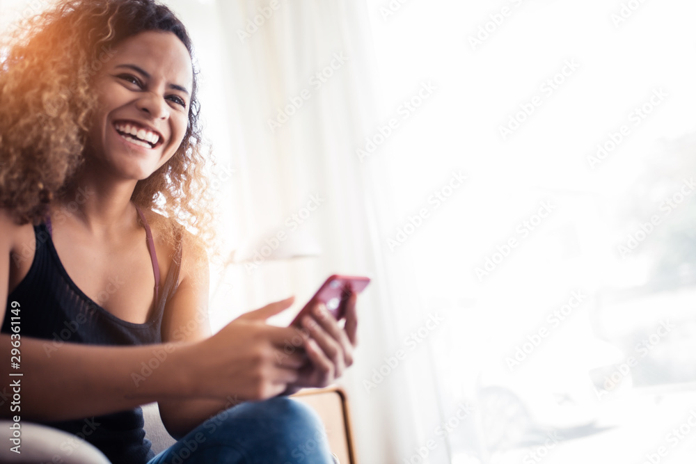 Girl watching a social media .African woman with beautiful smile hold mobile phone during rest in coffee shop near window. Girl watching a social media .African woman with beautiful smile hold mobile phone during rest in coffee shop near window.
