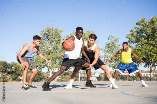 Young men playing basketball and dribbling ball on sports ground © AndrÈs Benitez/Westend61