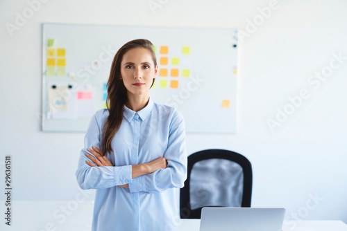 Portrait of confident businesswoman looking at camera with crossed arms in office