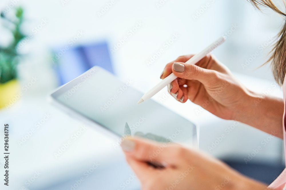 Close up of woman using pen and tablet in office Close up of woman using pen and tablet in office