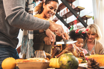 Thanksgiving Celebration Tradition Family Dinner Concept.family having holiday dinner and cutting turkey.Young black adult woman and her daughter happy..