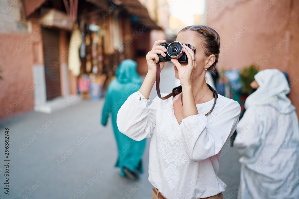 Tourism and technology. Happy young woman taking photo of  Marrakesh old town. Traveling by Morocco. - obrazy, fototapety, plakaty 