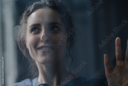 Profile of smiling young woman behind windowpane