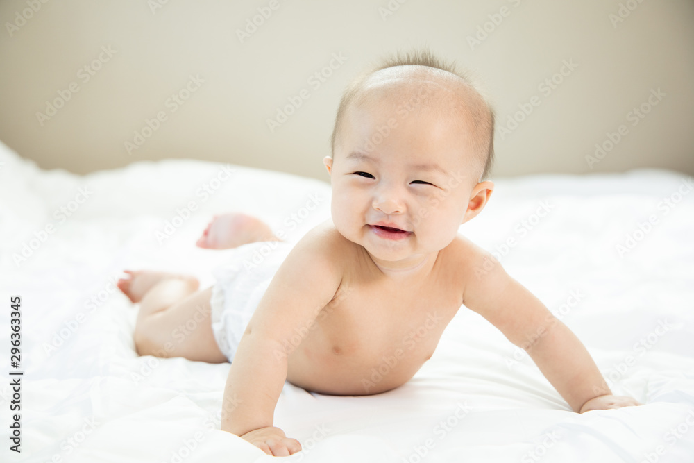 Asian baby happy in the room.Asian baby girl lying down on bed .