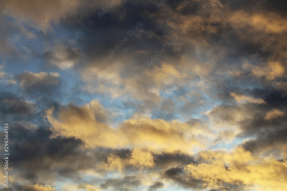 Fototapeta premium Golden fiery sunset in the blue sky. Crepuscular rays, streaming through gaps in clouds