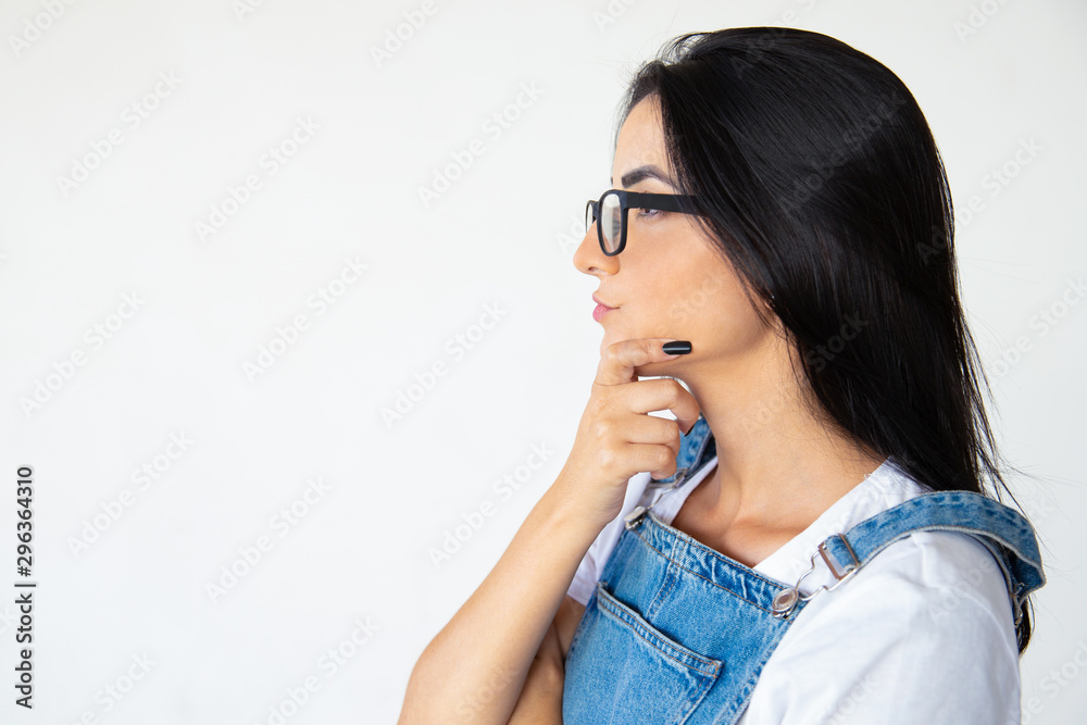 Side view of thoughtful young woman in eyeglasses. Serious brunette holding hand on chin. Thinking concept Side view of thoughtful young woman in eyeglasses. Serious brunette holding hand on chin. Thinking concept
