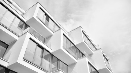  Fragment of a facade of a building with windows and balconies. Modern home with many flats. Black and white.