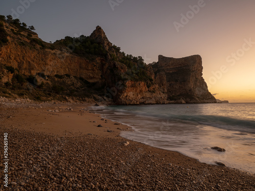  sunrise on beach with rocks in cala moraig photo