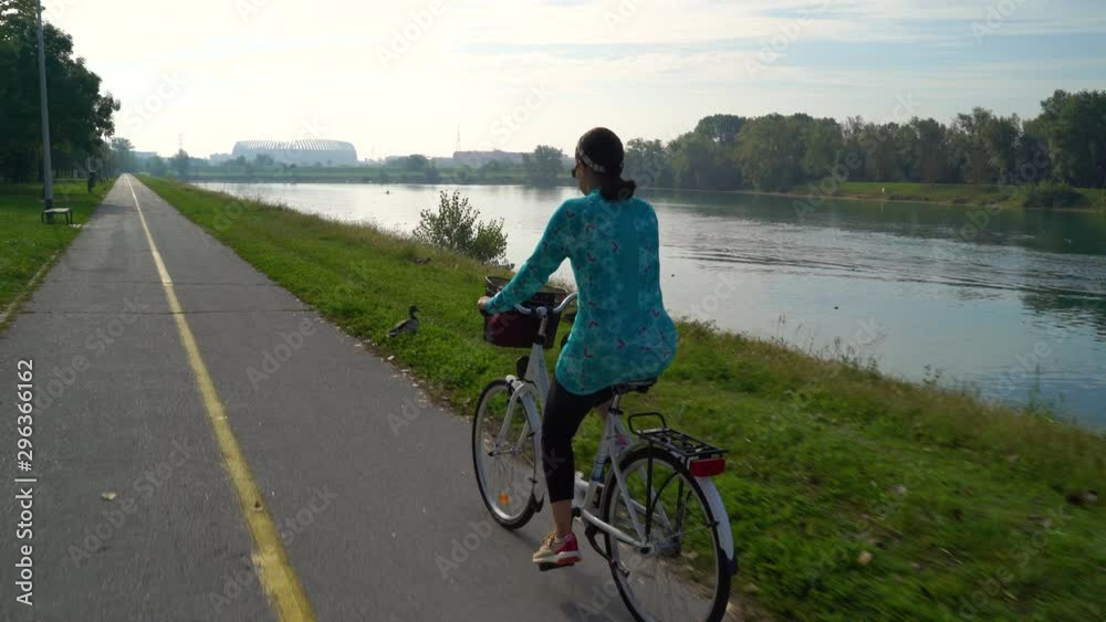 Middle age woman riding a bicycle during the morning at lake, Zagreb, Croatia. Middle age woman riding a bicycle during the morning at lake, Zagreb, Croatia.