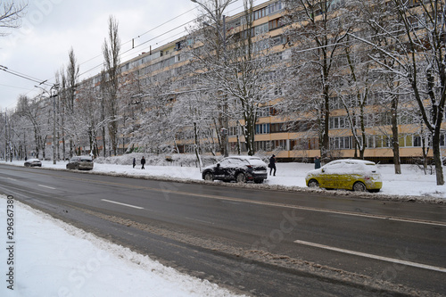 View across the asphalt road and cars away in the city in winter.