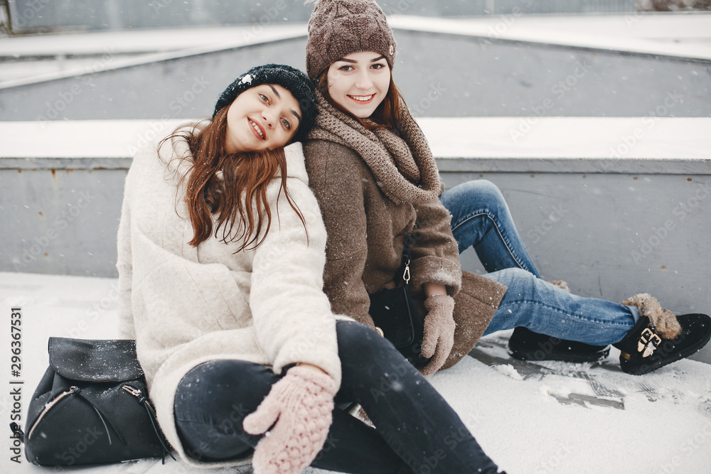Obraz premium two bright and merry girls sitting in the frozen snowy park