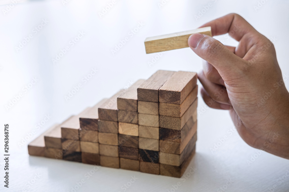 Alternative Risk and Strategy in business to make growth, Image of Business man's hand placing making a wooden block stacking hierarchy on growing to lay the foundation and development to successful Alternative Risk and Strategy in business to make growth, Image of Business man's hand placing making a wooden block stacking hierarchy on growing to lay the foundation and development to successful