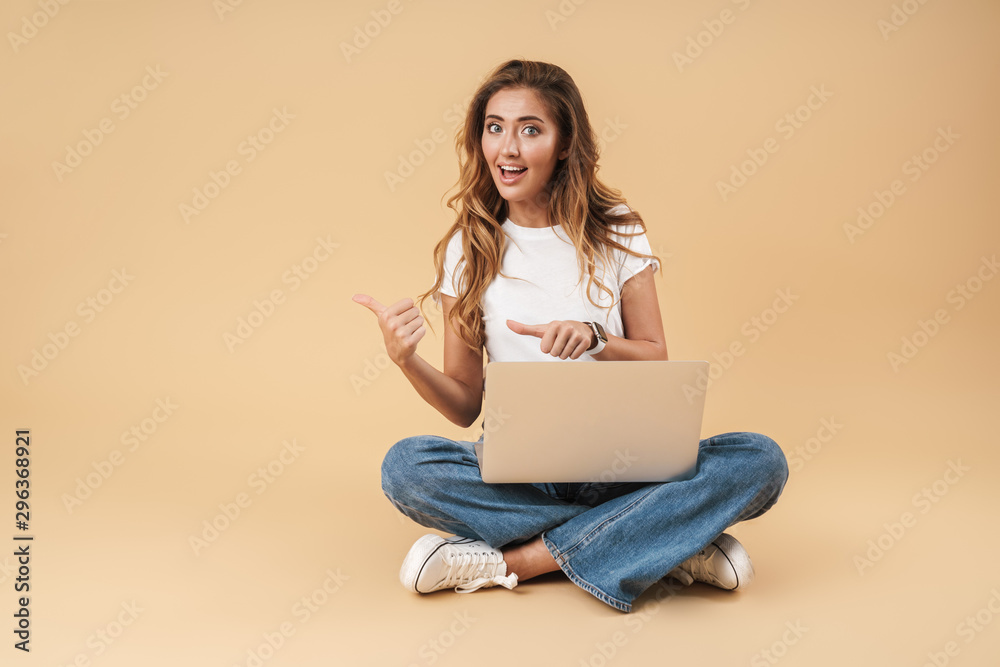 Image of beautiful woman sitting on floor with silver laptop Image of beautiful woman sitting on floor with silver laptop