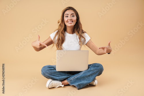 Image of happy woman using laptop while sitting on floor with legs crossed © Drobot Dean