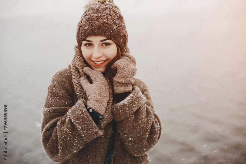 young and merry girl standing in the winter park near water young and merry girl standing in the winter park near water