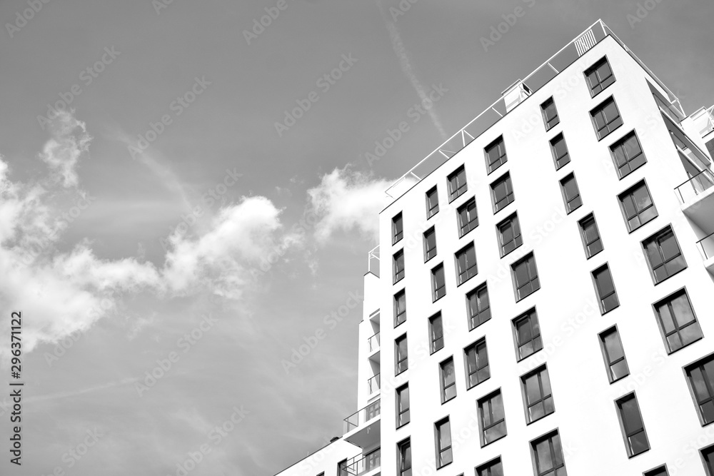 Fototapeta premium Fragment of a facade of a building with windows and balconies. Modern home with many flats. Black and white.