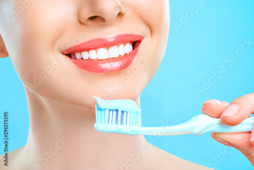 Young beautiful woman is engaged in cleaning teeth. Beautiful smile healthy white teeth. A girl holds a toothbrush. The concept of oral hygiene. Promotional image for a stomatology  dental clinic.