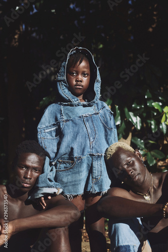 Portrait of girl wearing jacket standing near two shirtless men