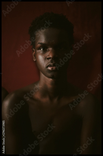 Portrait of shirtless boy near maroon colored wall